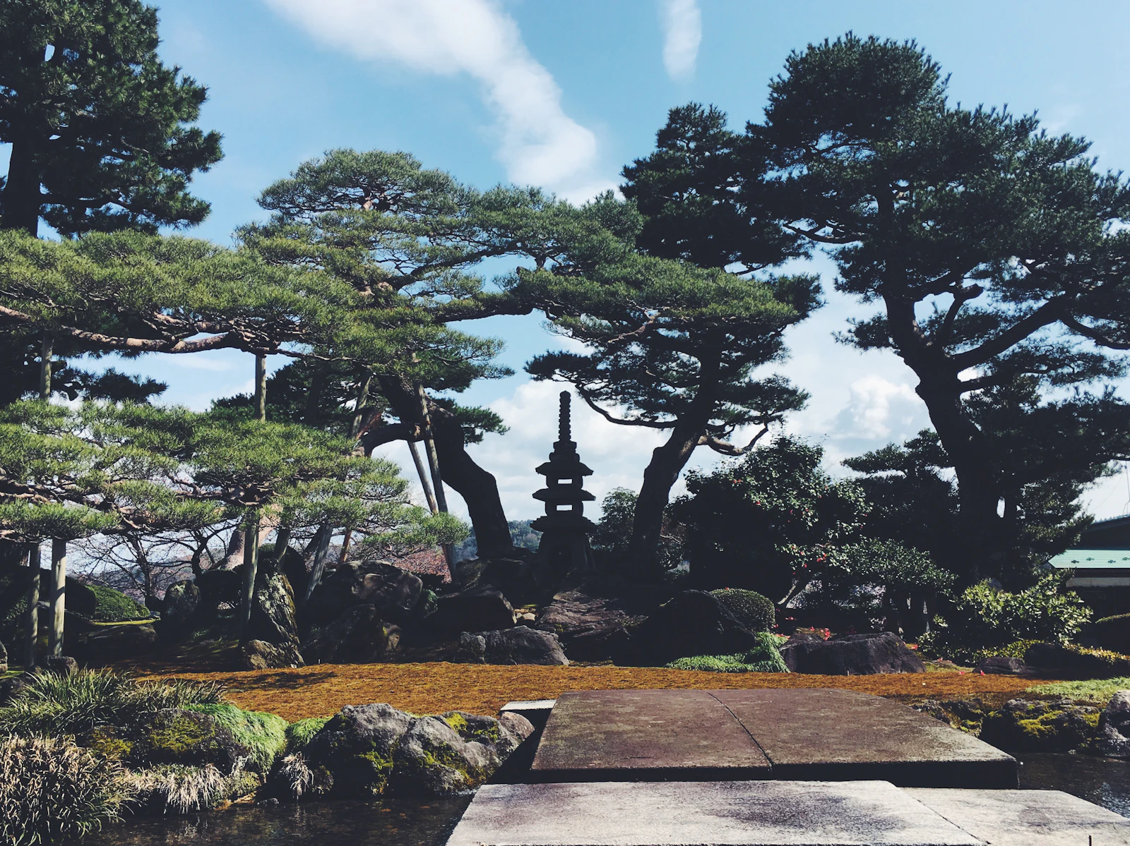 Jardim japonês com pagode de pedra entre pinheiros, em Kanazawa