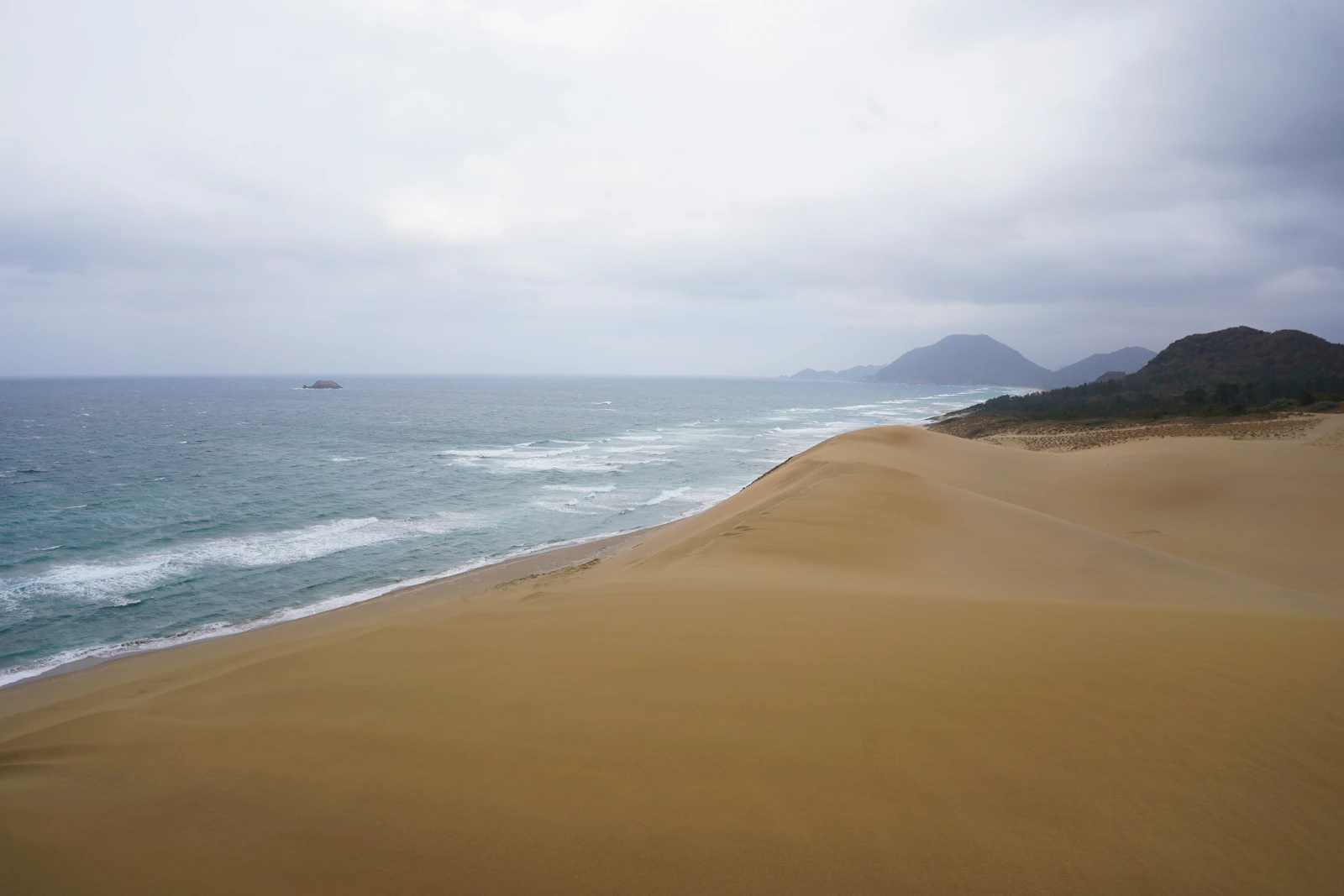 Dunas de areia de Tottori descendo até o Mar do Japão, sob céu nublado
